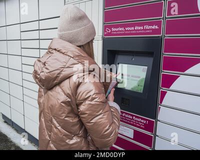 Loriol sur Drome, Frankreich - 14. Januar 2023: Abholung eines Pakets aus einem Mondial`Relay-Schließfach durch eine junge Frau. Schließfächer Mondial Relay. Pickup-Box. Stockfoto